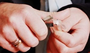 Zwei Hände halten einen Haustürschlüssel und stecken ihn in einen transparenten Schlüsselanhänger.