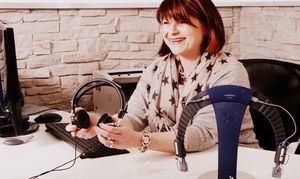 Frau im Büro am Schreibtisch mit Headset, Computer und Hörgeräte-Zubehör, Kundenservice